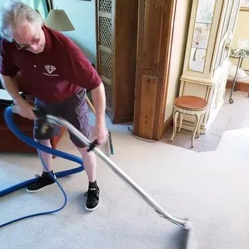 Crystal Clean technician vacuuming a living room carpet